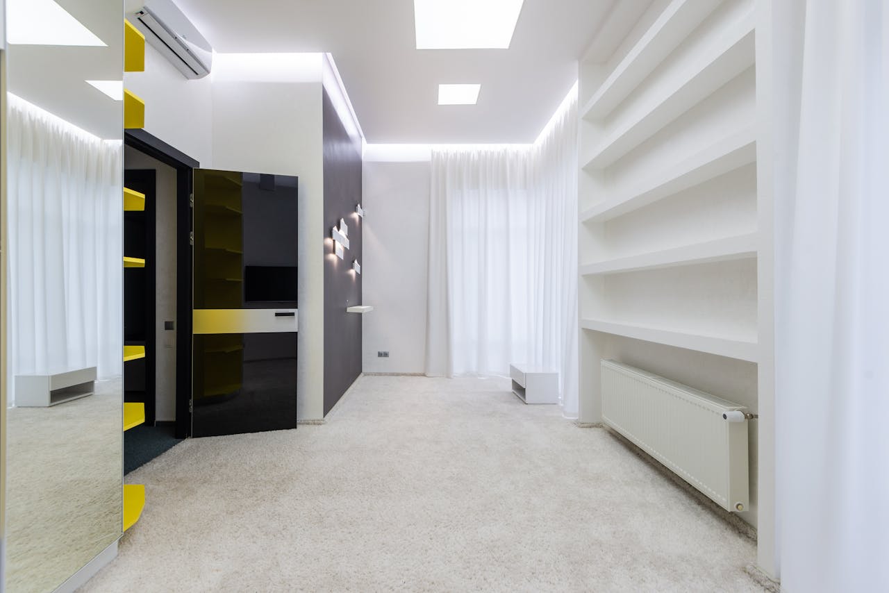 Creative design of empty room with radiator under shelves against mirror and door in light house
