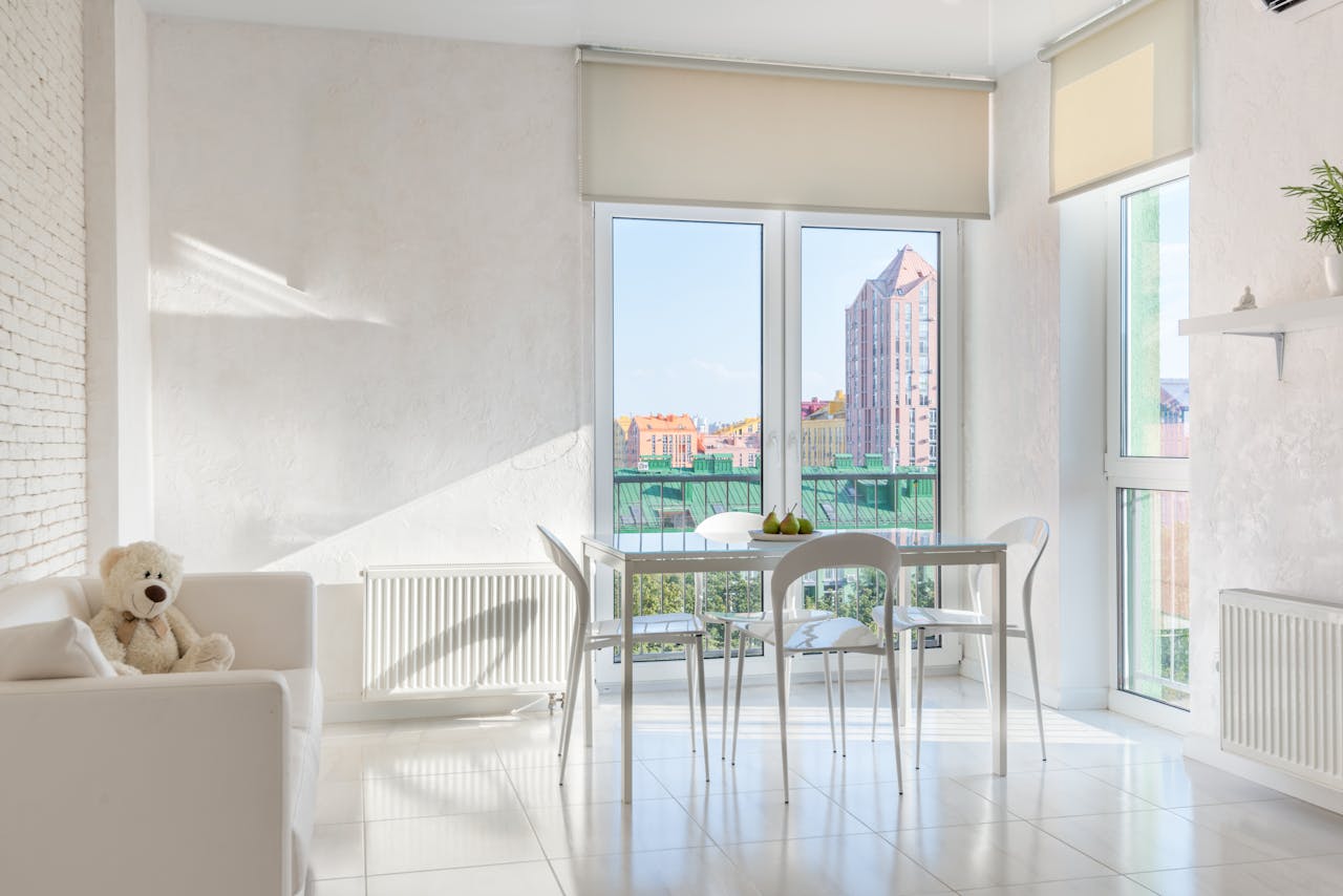 Interior of dining room with chairs at table placed near panoramic balcony doors and couch with plush toy
